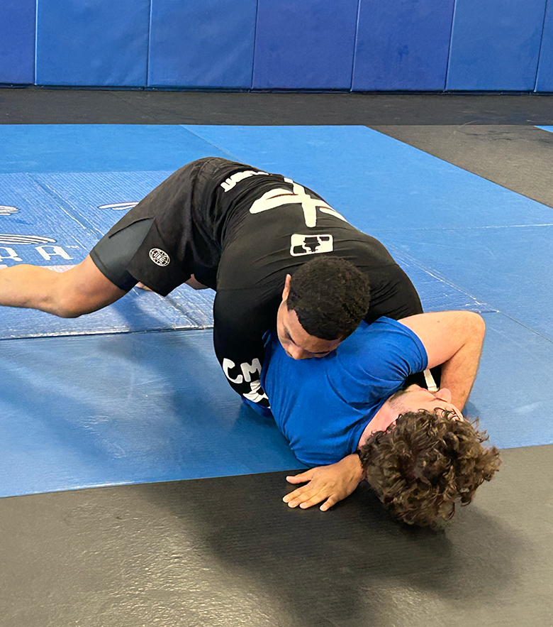 Two men Jiu-Jitsu spar on a mat.