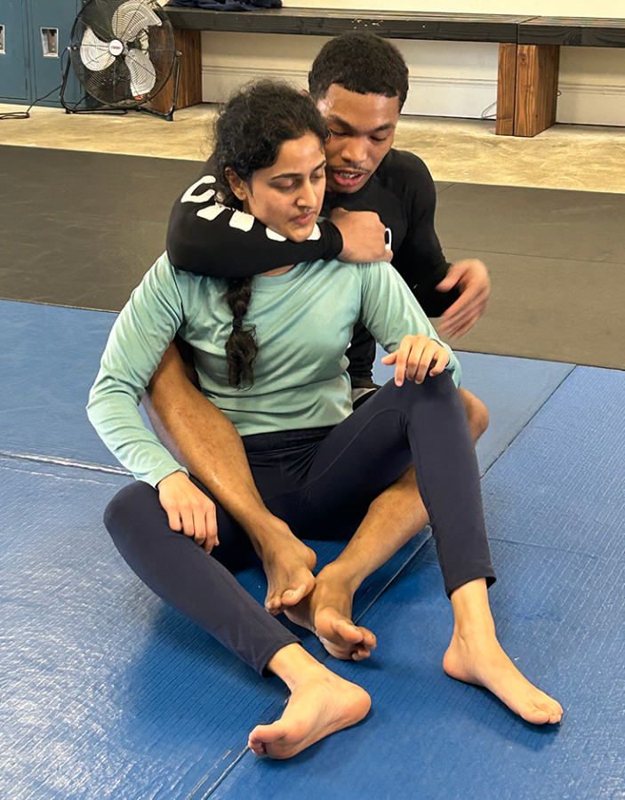 A man and a woman Jiu-Jitsu grapple on a mat.