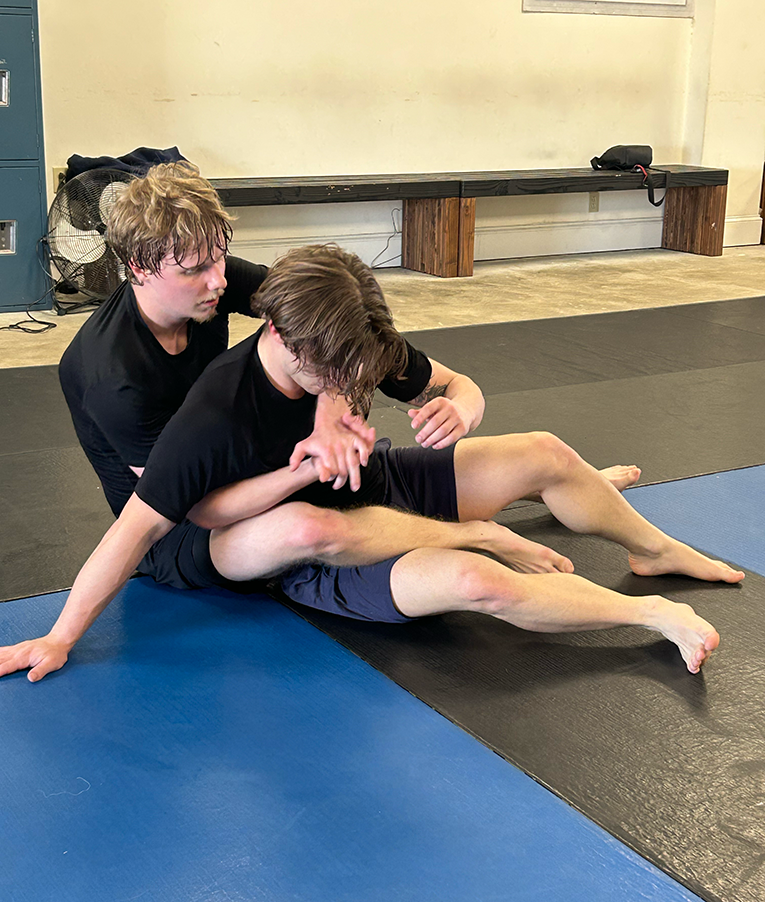 Two men Jiu-Jitsu spar on a mat.