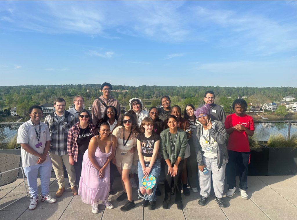 A group of students stand together outdoors on a rooftop posing for a photo during a campus cybersecurity event.