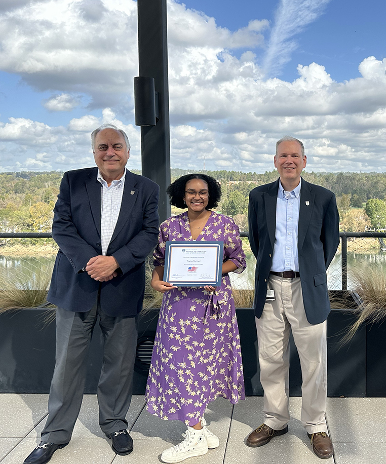 A woman holding a certificate between two men