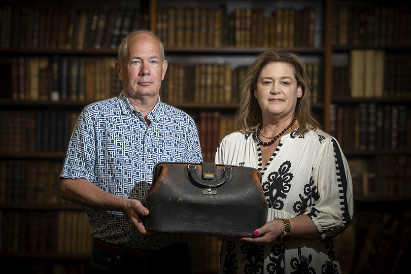 Man and woman holding an antique doctor's bag