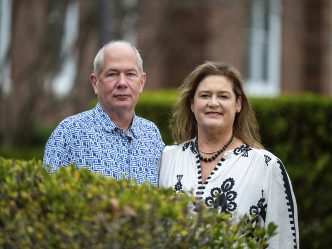 Man and woman standing behind a bush.