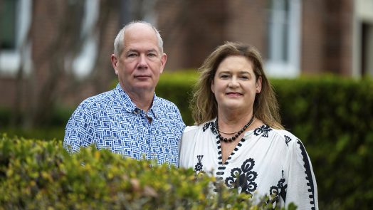Man and woman standing behind a bush.