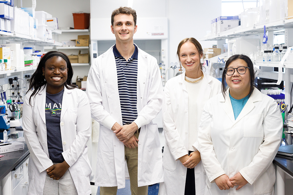 Three women and one man standing in a lab.