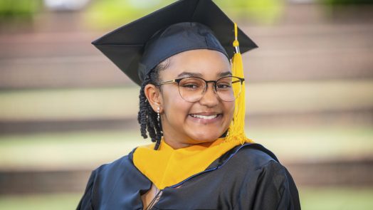 A woman smiles while posing for graduation photo