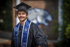 A man smiling with a cap and gown on