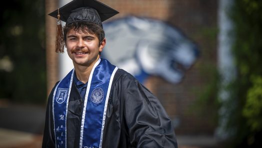 A man smiling with a cap and gown on