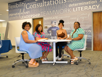 Four women sitting around a table at a meeting
