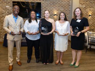 Smiling people holding award statues