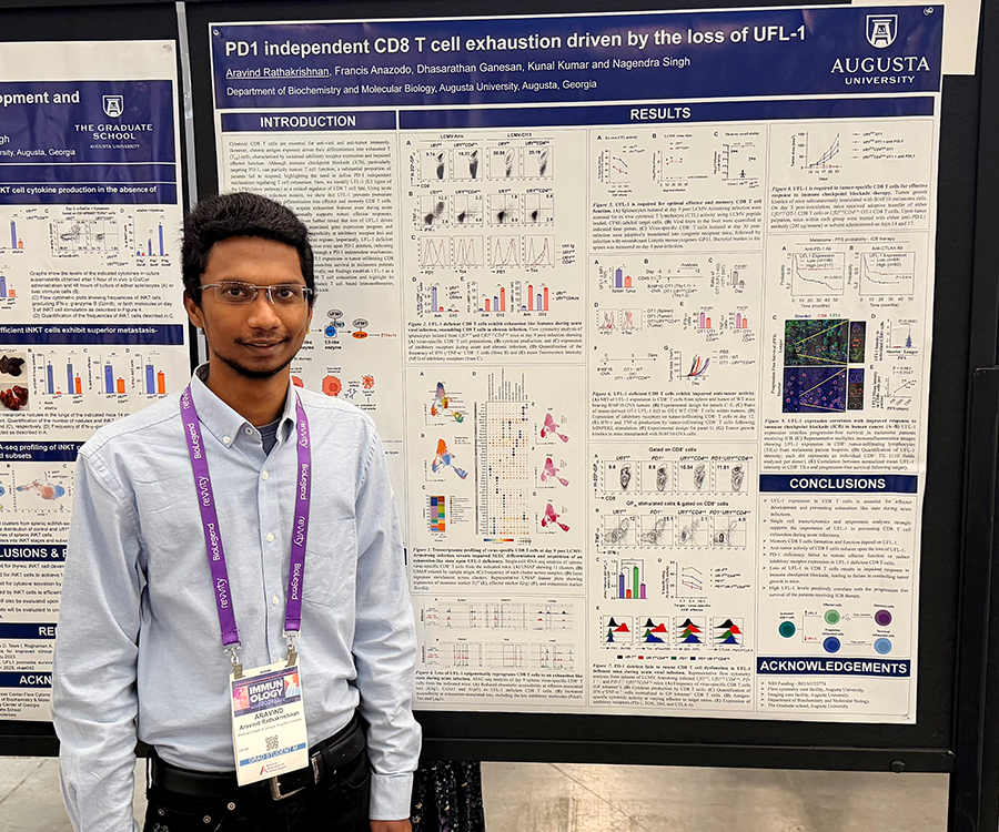 A man stands beside his scientific poster during a poster session at a large conference.