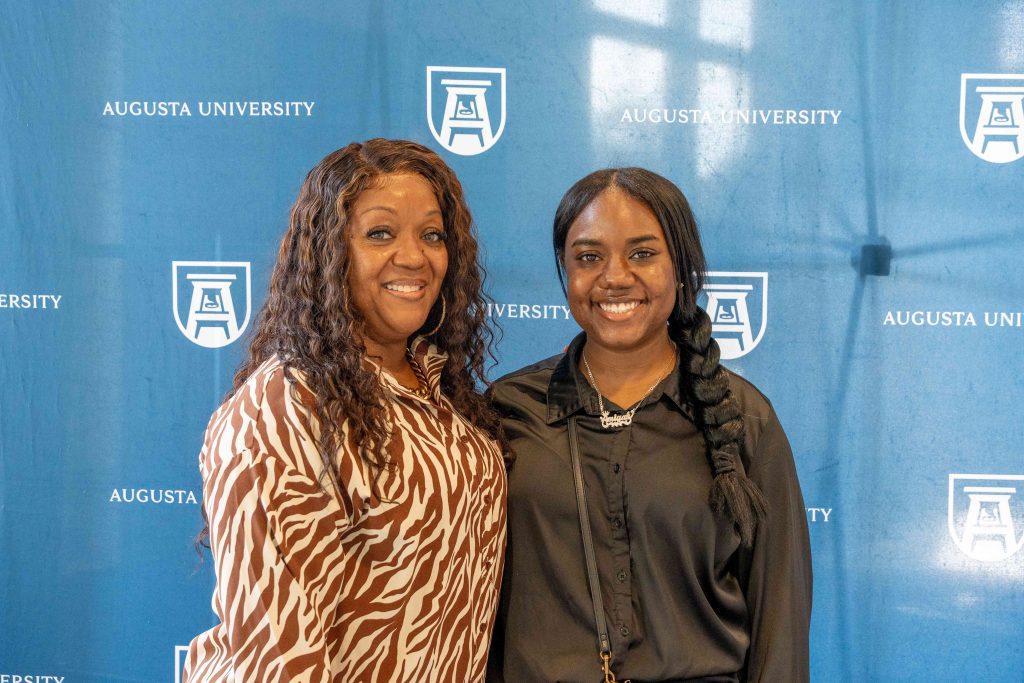 A high school-aged girl smiles beside an older woman.