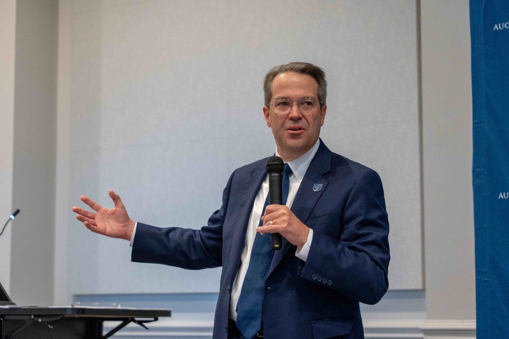 Augusta University President Russell T. Keen holding a microphone while speaking.