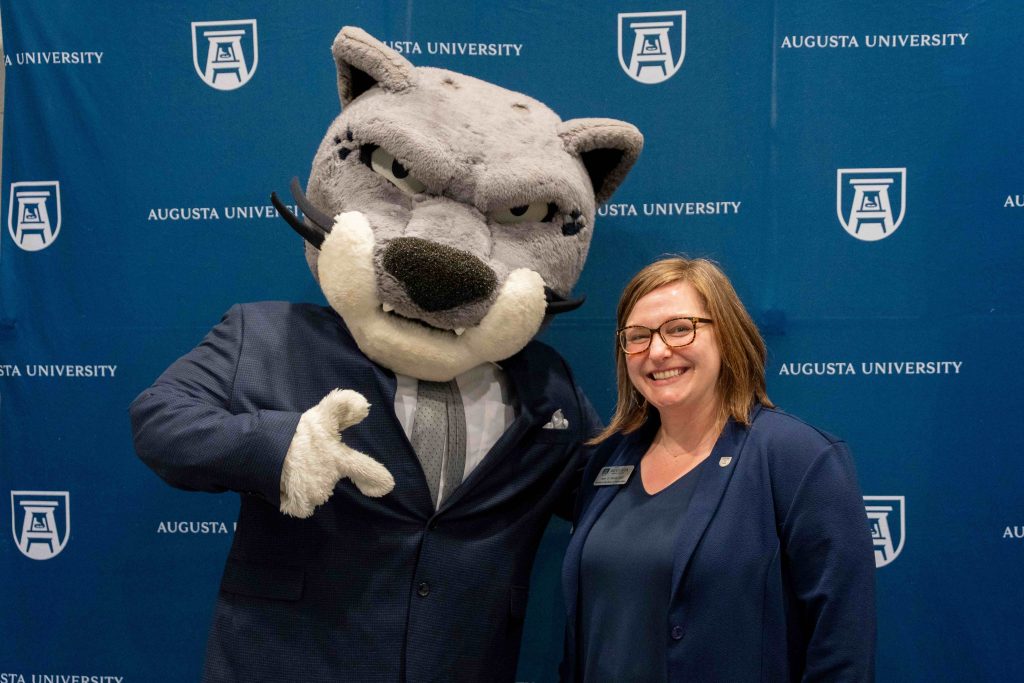 A jaguar mascot poses for a photo with a woman.