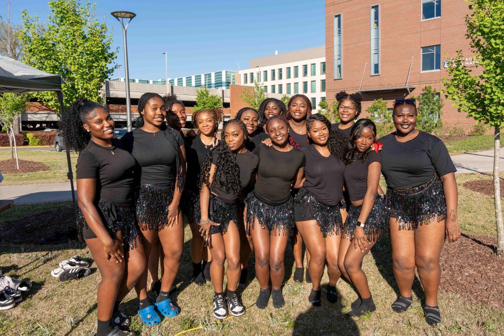 A group of girls in matching black outfits pose for a photo.