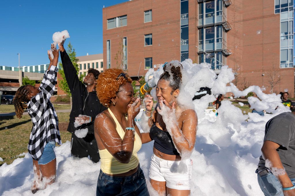 Two girls are smiling and laughing at one another while covered in foam.