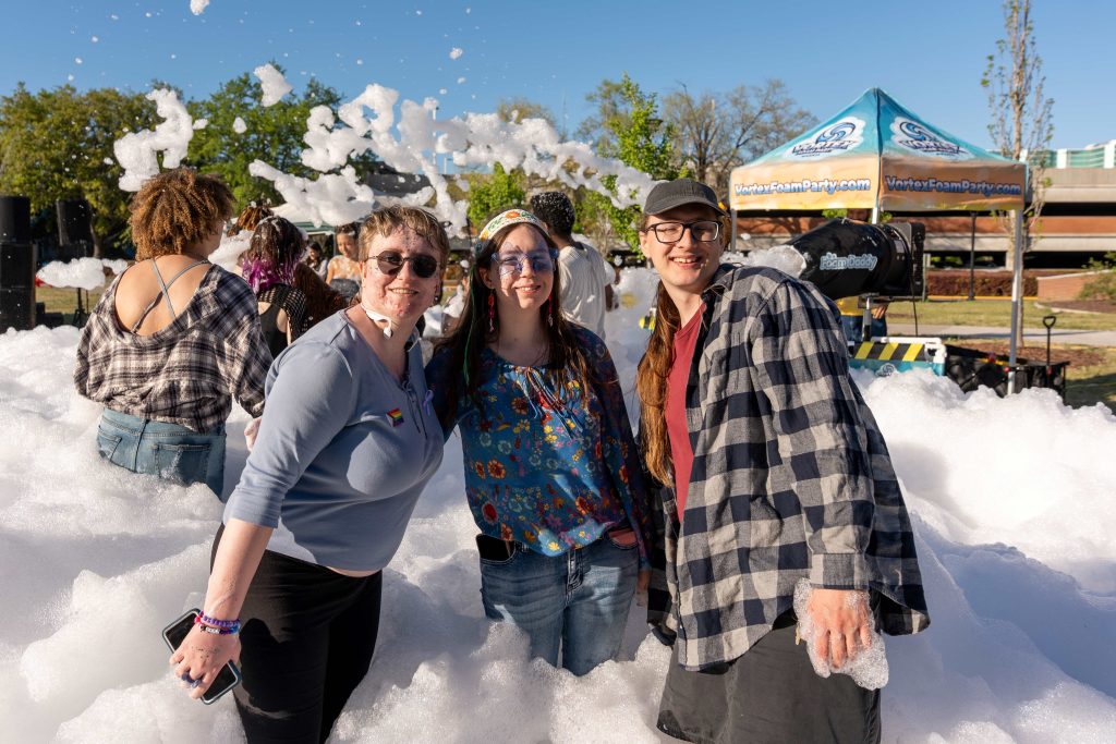 Three people pose for a photo while standing in the middle of a large foam pile.