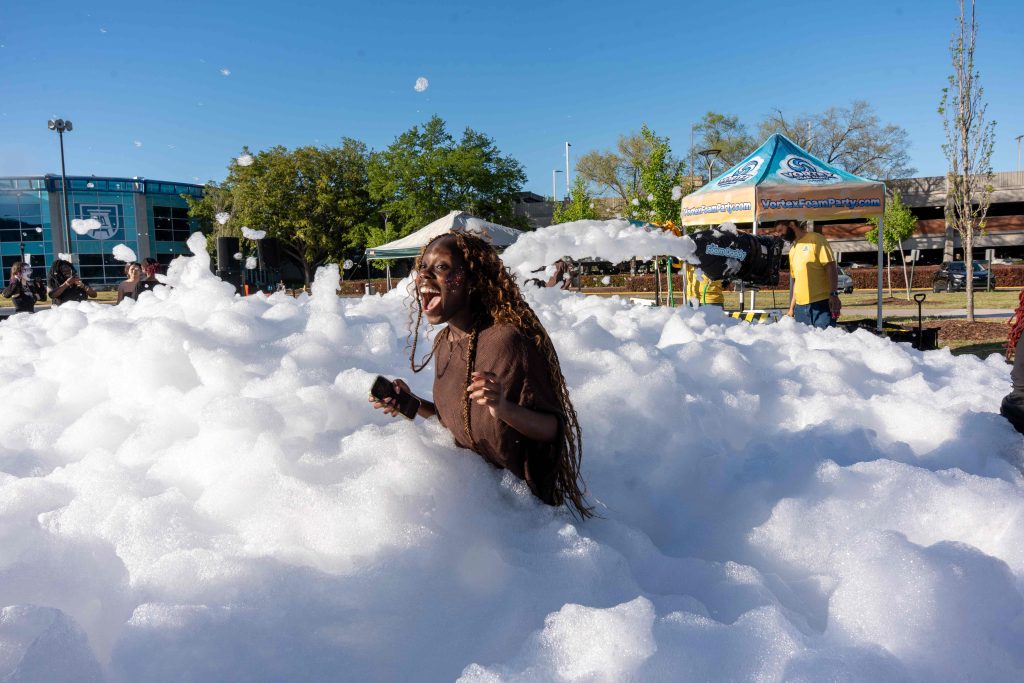 A girl screams in delight while standing in foam.