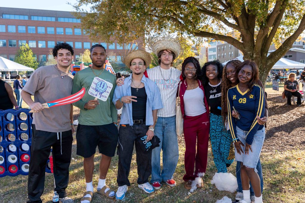 A large group of men and women pose for a photo outdoors. 