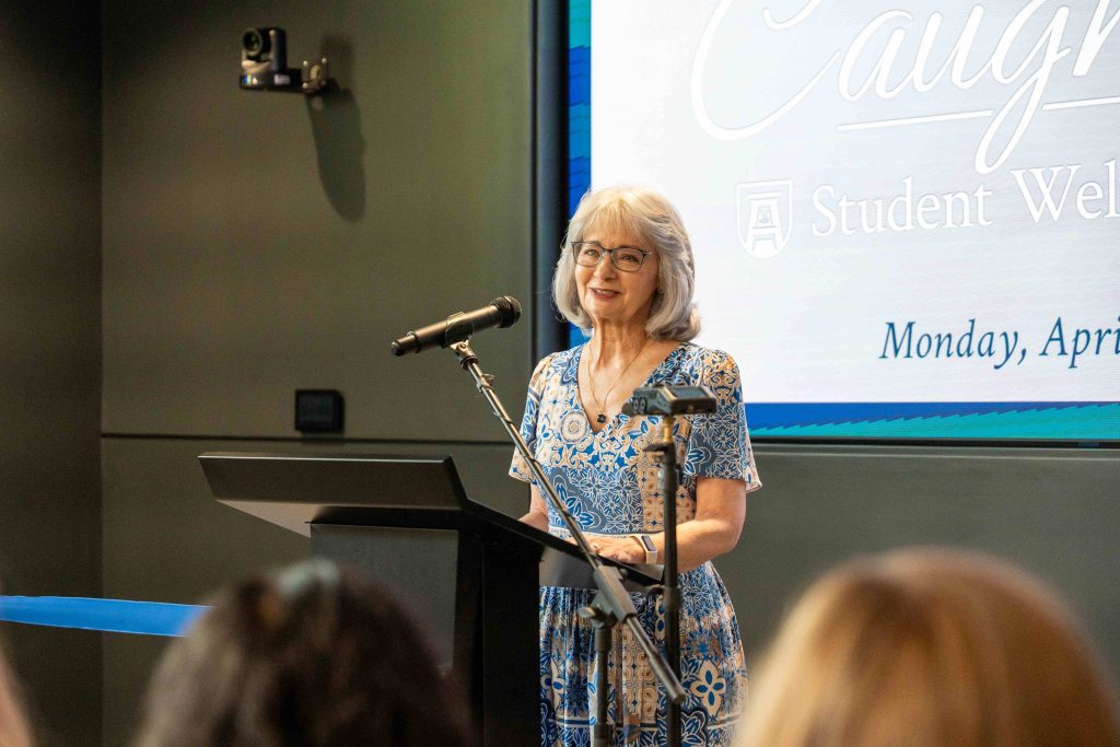 An older woman speaking into a microphone behind a podium.