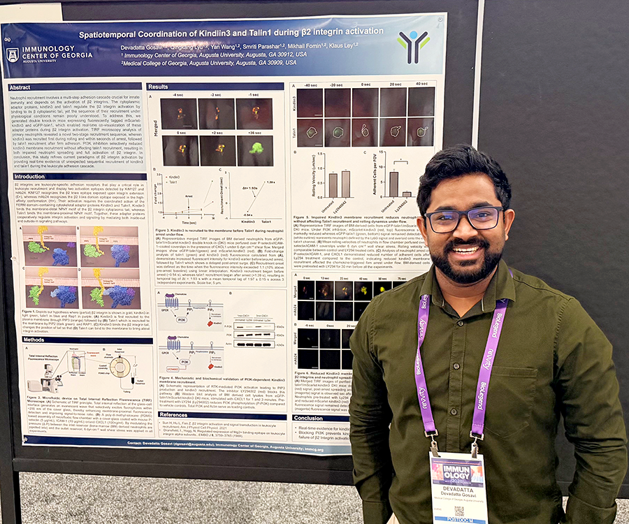 A man stands beside his scientific poster during a poster session at a large conference.