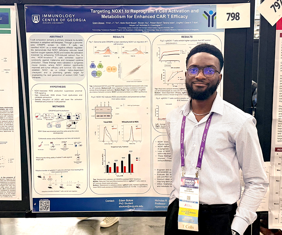 A man stands beside his scientific poster during a poster session at a large conference.