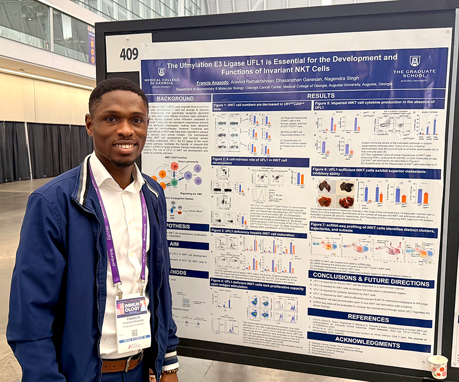 A man stands beside his scientific poster during a poster session at a large conference.