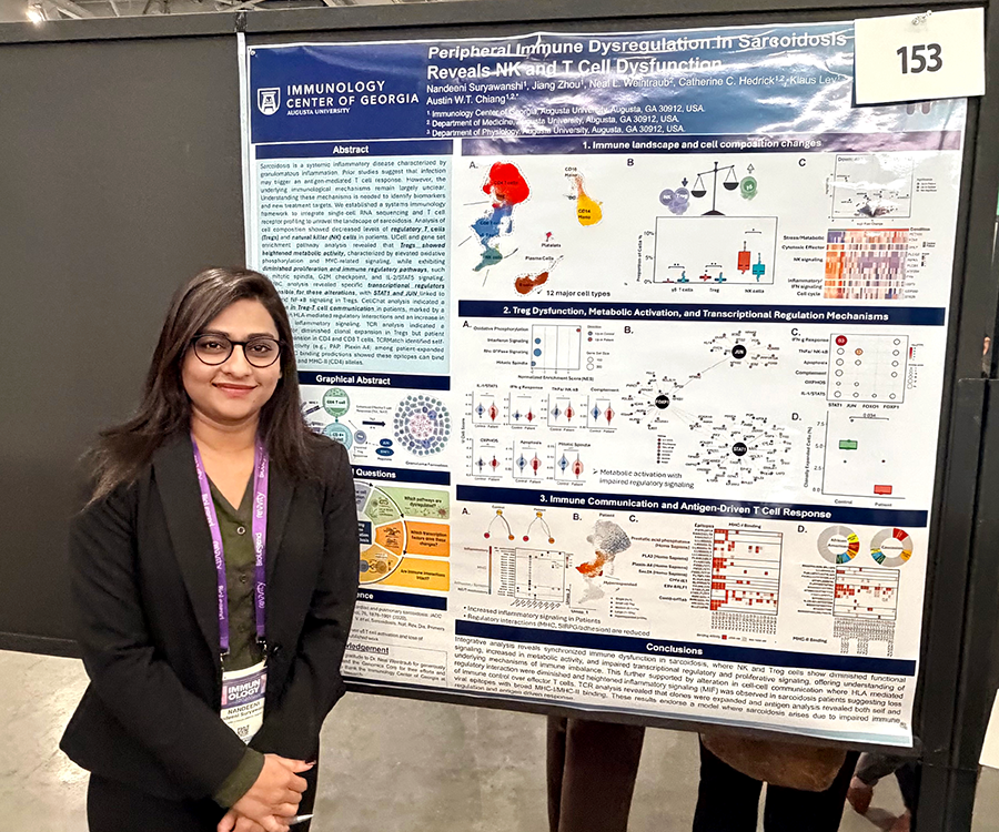 A woman stands beside her scientific poster during a poster session at a large conference.