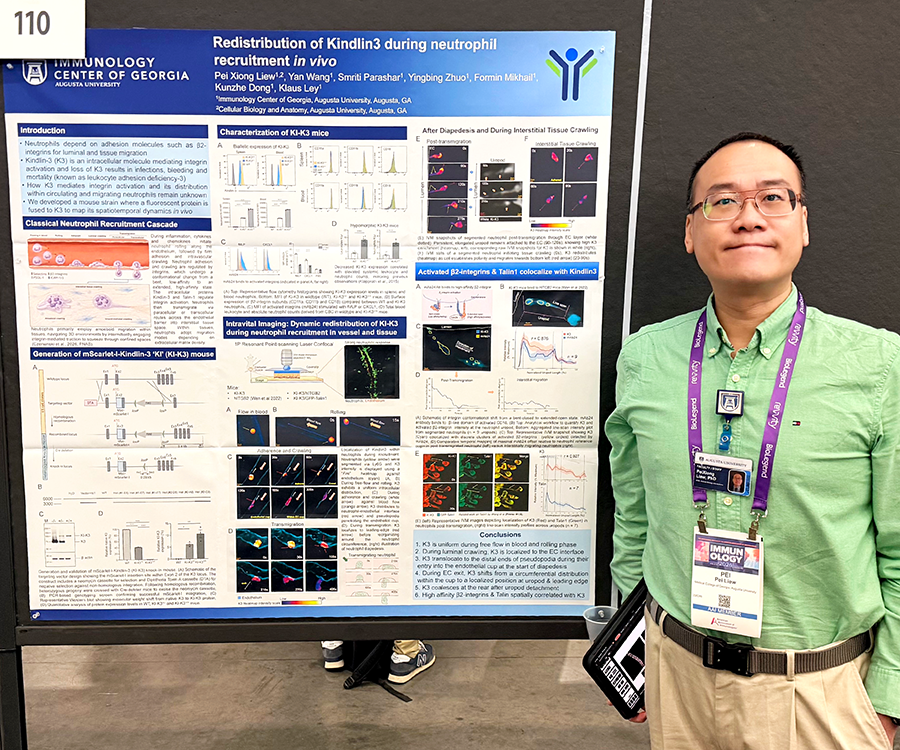 A man stands beside his scientific poster during a poster session at a large conference.