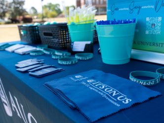 A table that includes various Augusta University and Sexual Assault Month branded items, including bracelets, pens and hanker chiefs.