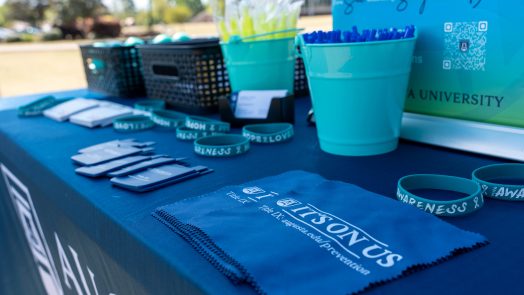A table that includes various Augusta University and Sexual Assault Month branded items, including bracelets, pens and hanker chiefs.