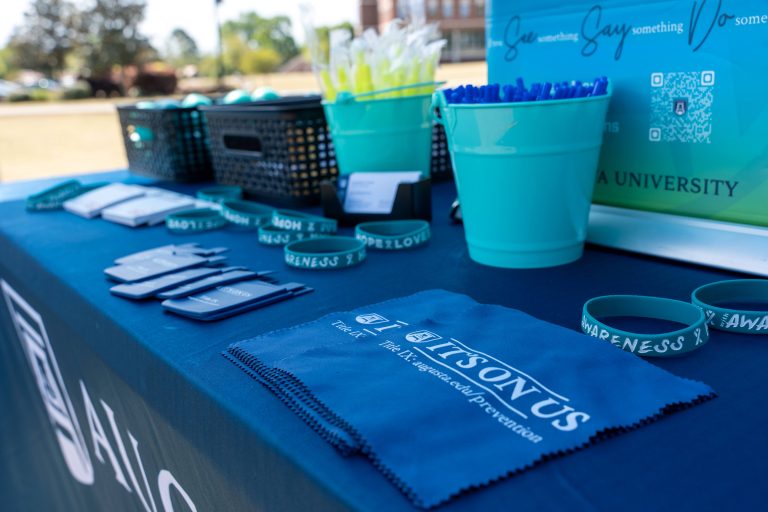 A table that includes various Augusta University and Sexual Assault Month branded items, including bracelets, pens and hanker chiefs.