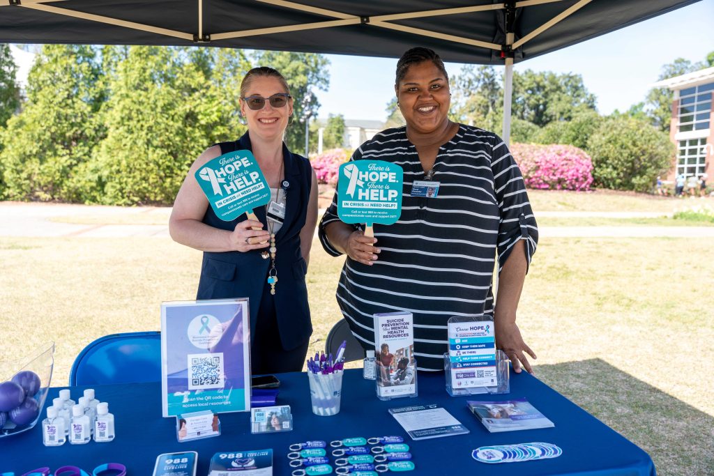 Tabling participants holding office fans while smiling for a photo.