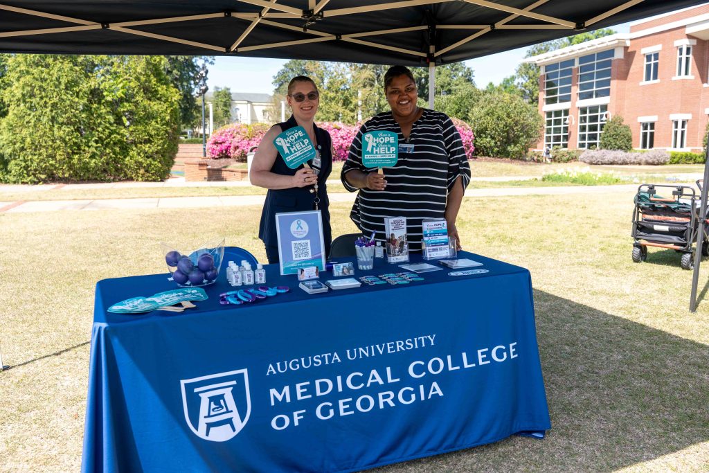 Tabling participants holding office fans while smiling for a photo.