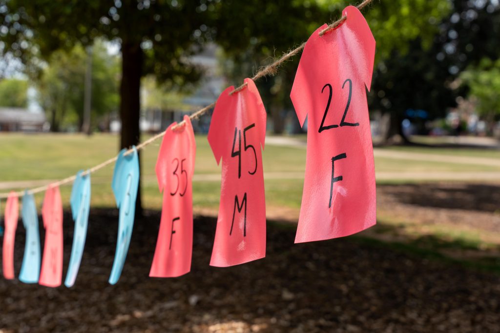 Blue and red plastic-shaped shirts hang on a clothesline outdoors.