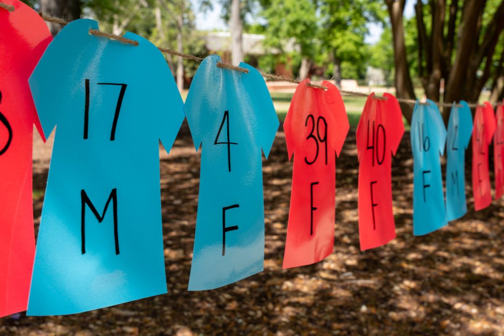 Blue and red plastic-shaped shirts hang on a clothesline outdoors.
