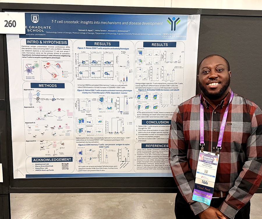 A man stands beside his scientific poster during a poster session at a large conference.