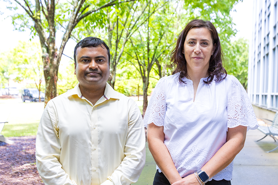 A man and a woman stand outside of a large modern research building.