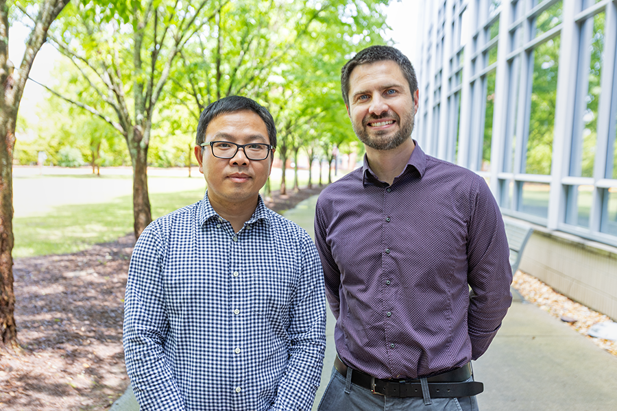 Two men stand outside of a large modern research building.