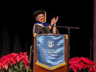 A woman standing behind a podium clapping