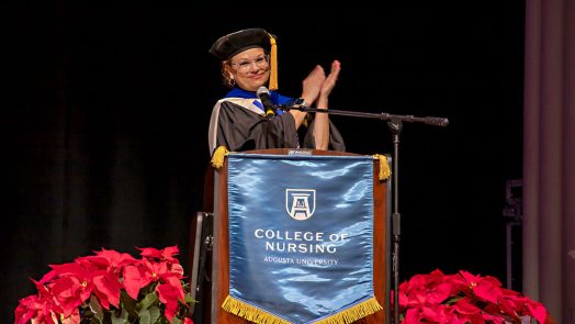 A woman standing behind a podium clapping