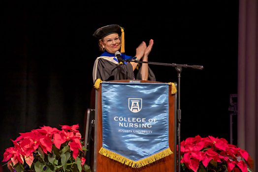 A woman standing behind a podium clapping