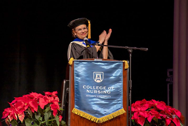 A woman standing behind a podium clapping