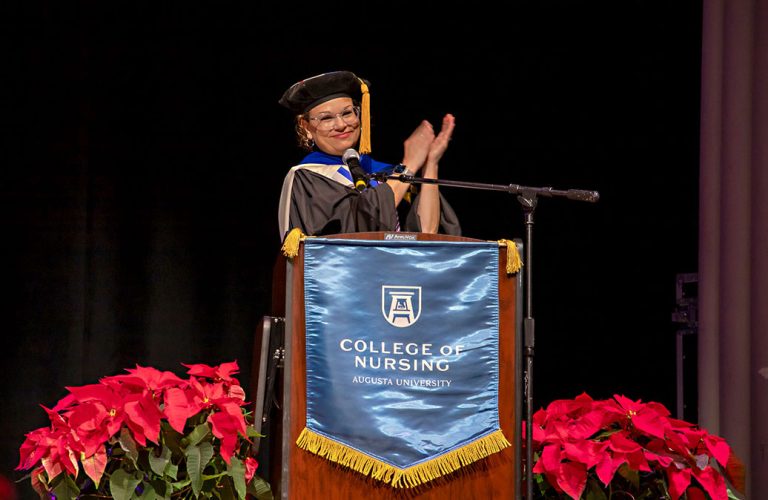 A woman standing behind a podium clapping