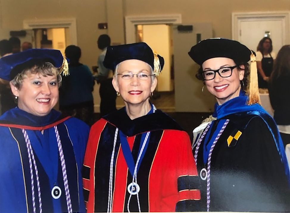 Three women standing in graduation regalia