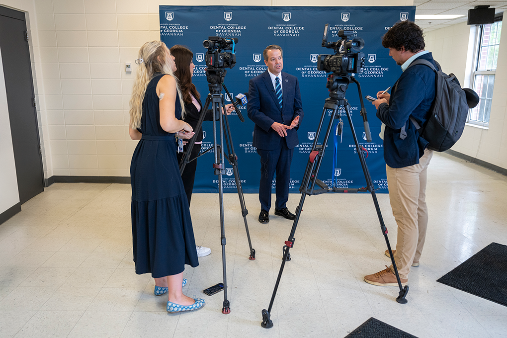 A male and female reporter interview a man in a suit.