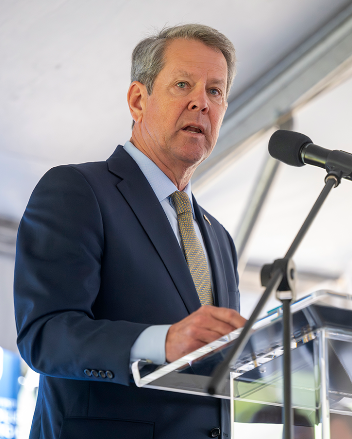A man in a suit stands behind a podium and delivers a speech.