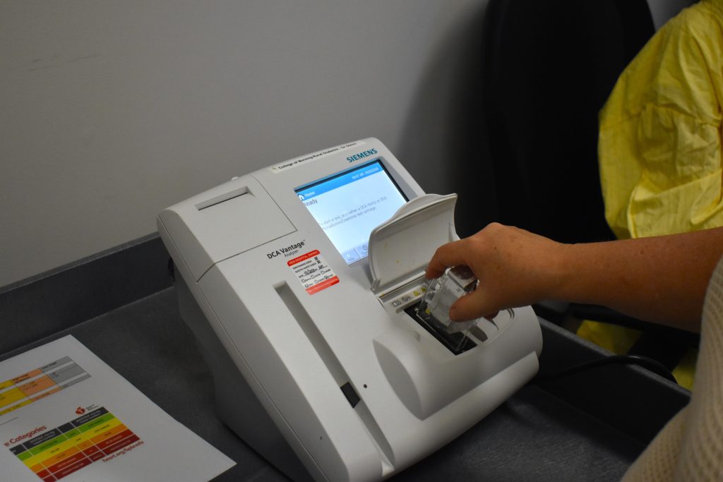 A device on top of a cart, a hand is putting in a sample port