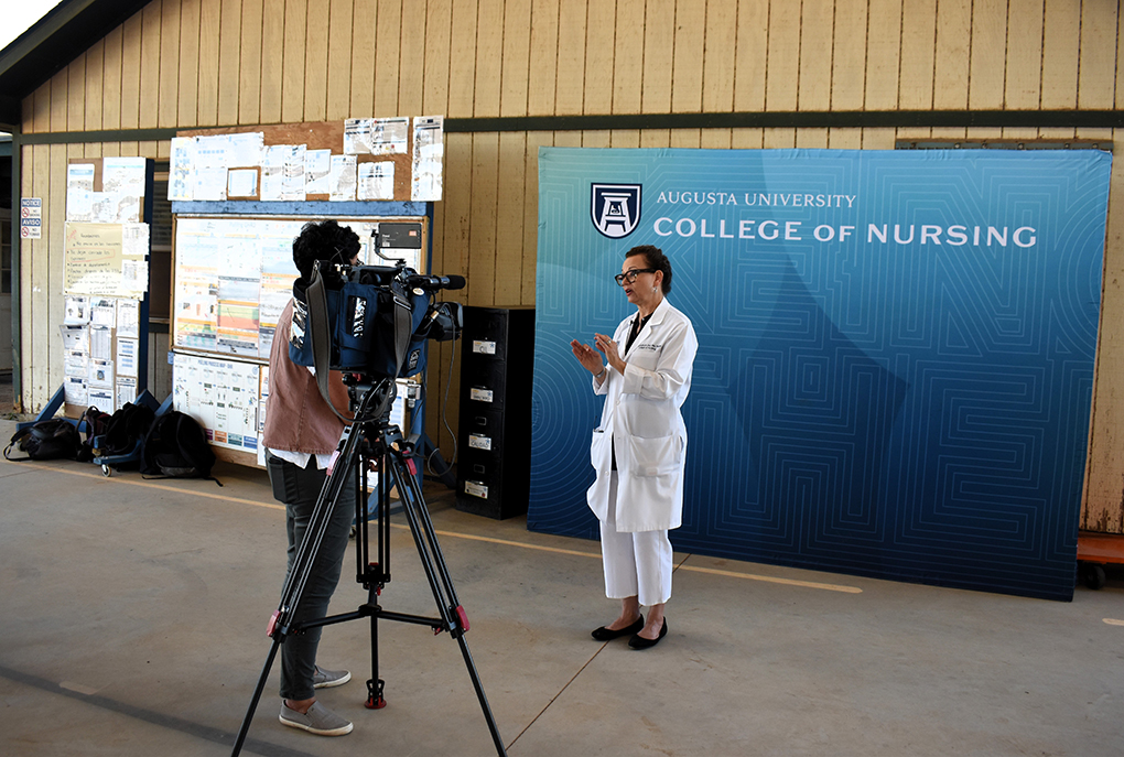 Woman standing in front of a screen being interviewed
