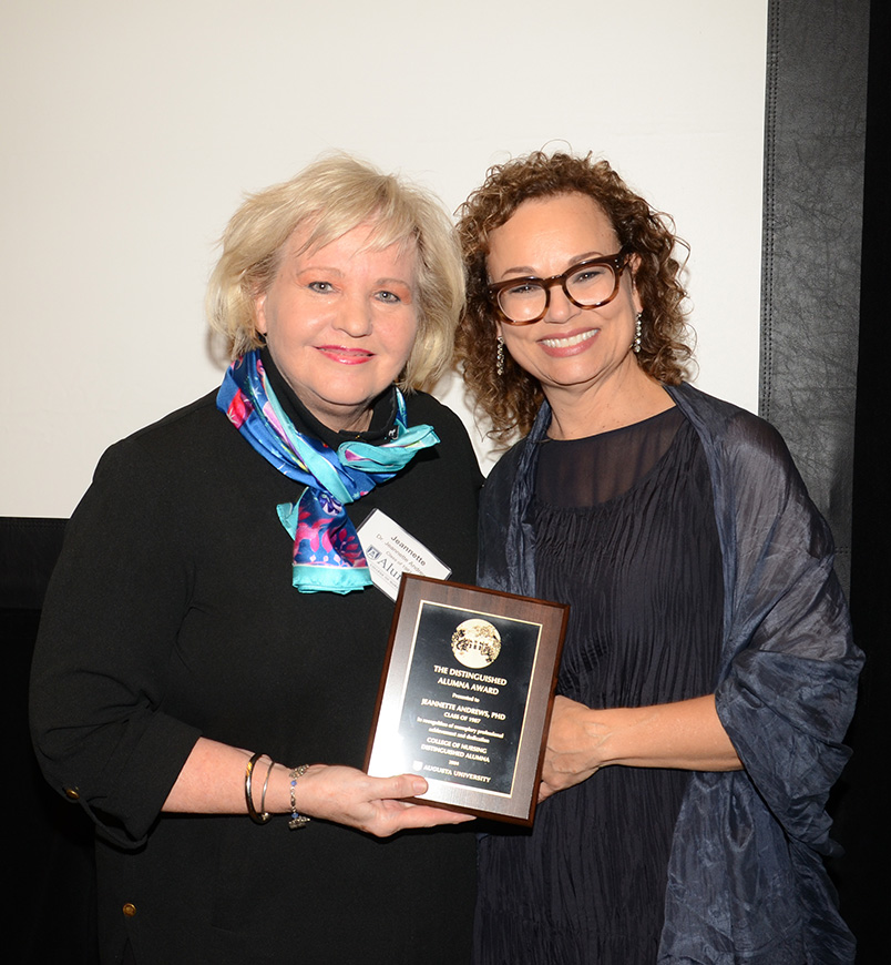 Two women standing holding a plaque